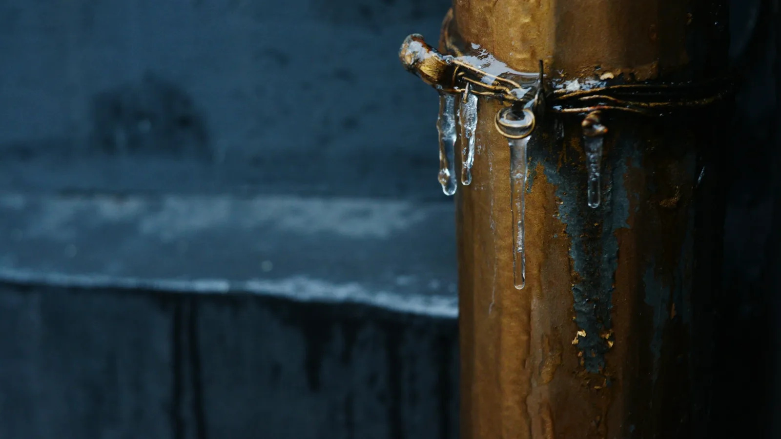 Icicles hanging from a copper pipe in winter, a warning to learn how to prevent frozen pipes